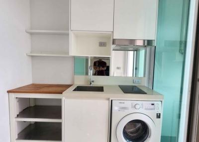 Modern kitchen with white cabinetry, washing machine, and wooden countertops