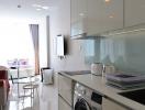 Modern kitchen with white cabinets adjacent to a cozy living area