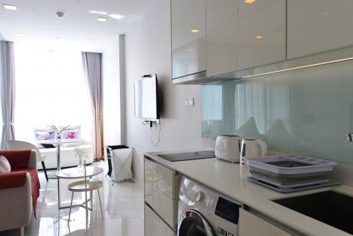 Modern kitchen with white cabinets adjacent to a cozy living area