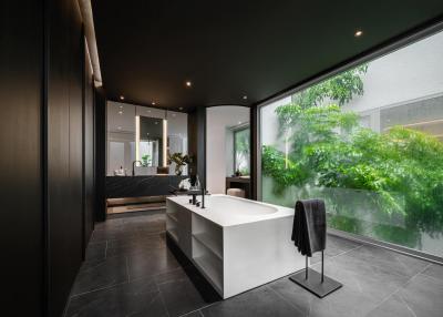 Modern bathroom with large bathtub, dark tiles, and natural light