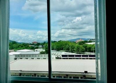 View from a window overlooking nearby buildings and lush greenery