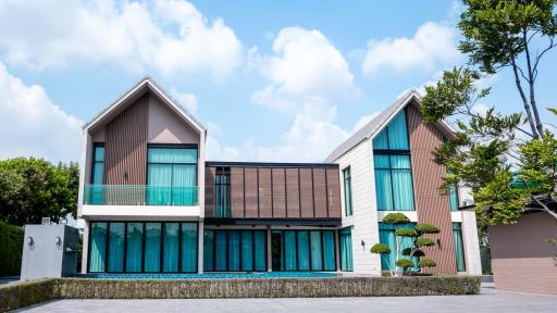 Modern two-story residential home with large windows and a lush garden