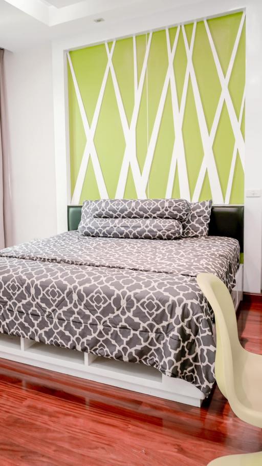 Modern bedroom with a stylish green and white accent wall and patterned bedding