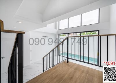 Spacious and bright living room with high ceiling and large windows leading to a balcony with a pool view