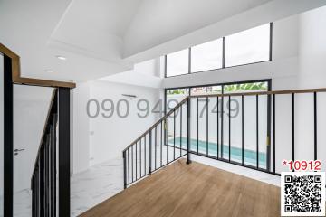 Spacious and bright living room with high ceiling and large windows leading to a balcony with a pool view