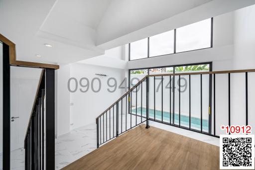 Spacious and bright living room with high ceiling and large windows leading to a balcony with a pool view