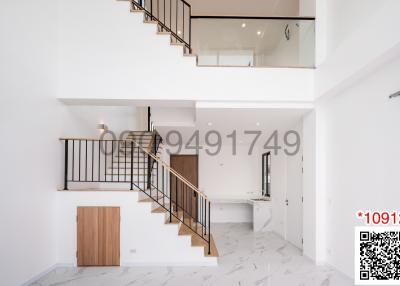 Elegant interior view of a building featuring a staircase, high ceiling, and minimalist design