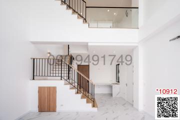 Elegant interior view of a building featuring a staircase, high ceiling, and minimalist design