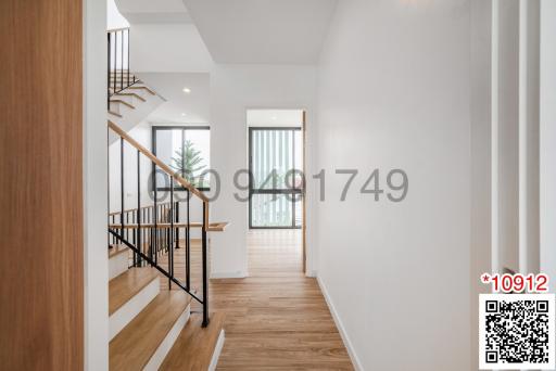 Spacious and bright hallway with wooden flooring and stair access