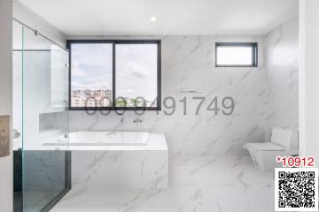 Modern bathroom with marble tiles, large windows, and glass shower