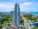 Aerial view of a modern high-rise residential building against a coastal city backdrop