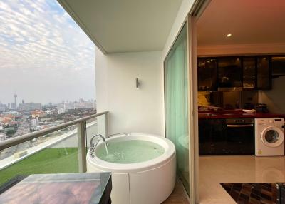 Spacious balcony with a jacuzzi, view of the city, and laundry area