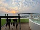 Spacious balcony with ocean view, bar stools, and a luxurious bathtub at sunset