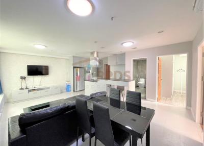 Open plan living room with adjacent kitchen, modern furnishings, and ample lighting