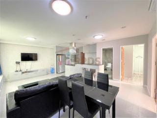 Open plan living room with adjacent kitchen, modern furnishings, and ample lighting