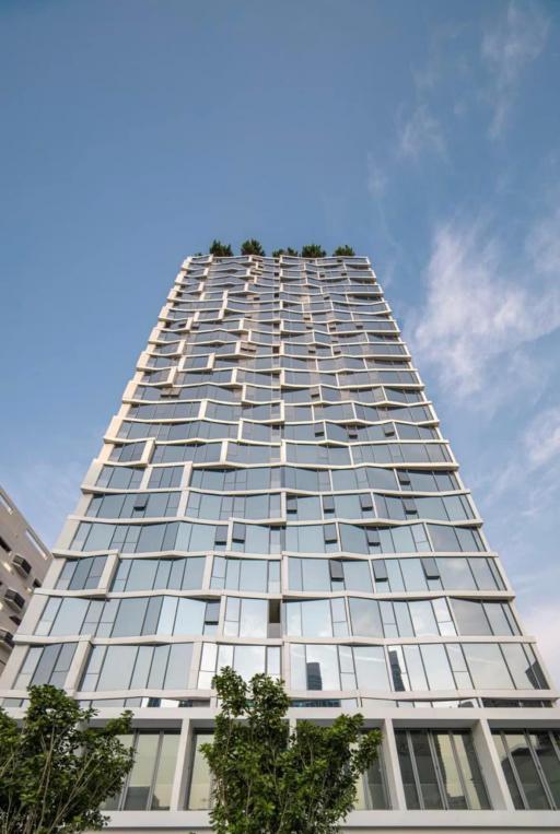 Modern high-rise residential building with balconies and lush rooftop garden