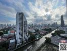 High-rise building beside a river with city skyline and moving boat