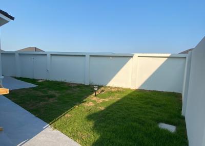 A small, fenced backyard with fresh green grass and ample sunlight