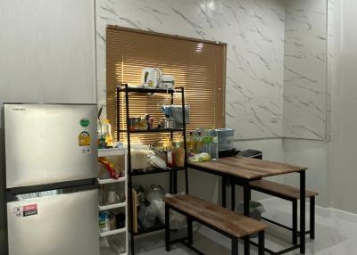 Modern kitchen with marble wall tiles and glossy floor, equipped with refrigerator and small wooden dining set