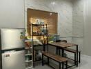 Modern kitchen with marble wall tiles and glossy floor, equipped with refrigerator and small wooden dining set