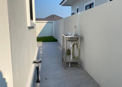 Narrow outdoor corridor with a utility sink and wall-mounted faucet