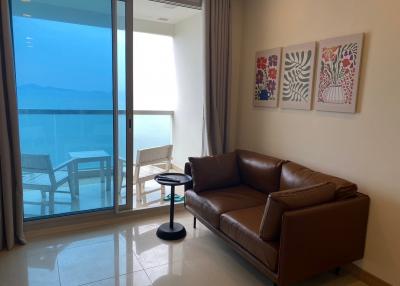 Modern living room with ocean view, leather sofa, and balcony access