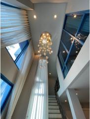Modern high-ceiling interior with unique chandelier and tall windows