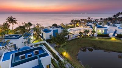 Aerial view of modern luxury villas at twilight with ocean and sunset sky