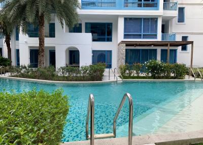 Modern multi-story building with balconies facing a communal swimming pool