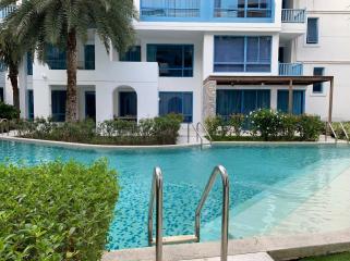 Modern multi-story building with balconies facing a communal swimming pool