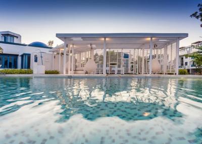 Luxurious outdoor pool area with white pergola and stylish hanging chairs