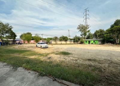 Spacious open lot with a vehicle and surrounding buildings under clear skies