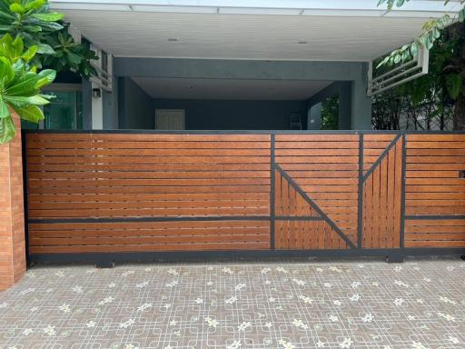 Modern house entrance with wooden gate and tiled driveway