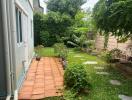 Lush green garden space next to a residential building with a paved pathway