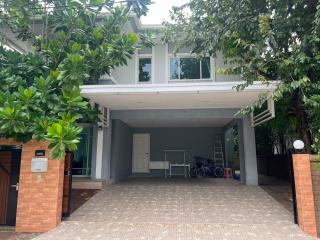 Modern two-story house with a covered parking area and lush greenery