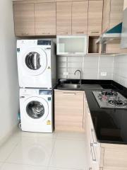 Modern kitchen with stacked washer and dryer, microwave, and gas stove
