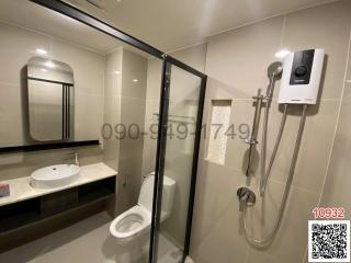 Modern bathroom with glass shower enclosure, wall-mounted toilet, and vanity