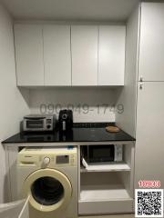 Compact kitchen with white cabinets, washing machine, and microwave