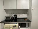 Compact kitchen with white cabinets, washing machine, and microwave