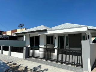 White single-story house with gray roofing and a small front porch behind a black metal fence