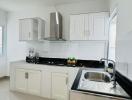 Modern kitchen with white cabinetry and black countertops