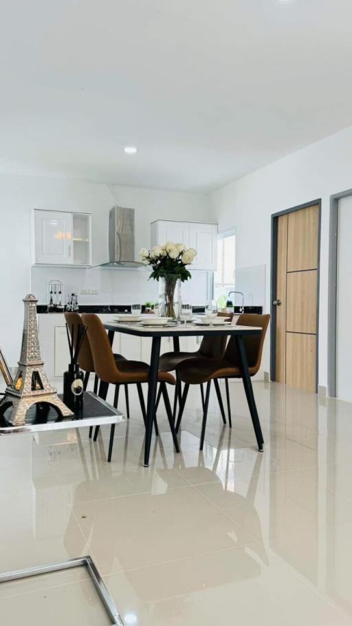 Modern white themed kitchen with dining table set and decorative Eiffel tower sculpture