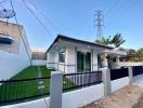 Modern single-story house with a well-manicured lawn and a perimeter fence