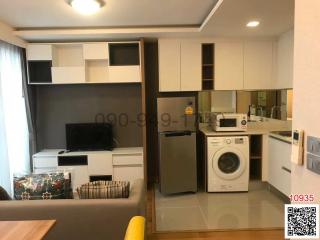 Compact living room with integrated kitchenette featuring modern appliances and cabinetry