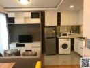 Compact living room with integrated kitchenette featuring modern appliances and cabinetry