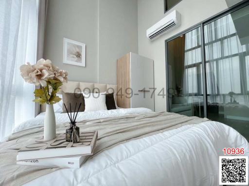 Modern bedroom with a comfortable bed, artwork, and floor-to-ceiling windows