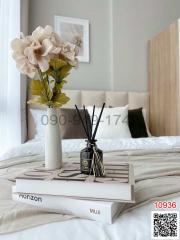 Cozy bedroom corner with a stylish tabletop arrangement including books, flowers, and scent diffuser