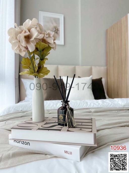 Cozy bedroom corner with a stylish tabletop arrangement including books, flowers, and scent diffuser