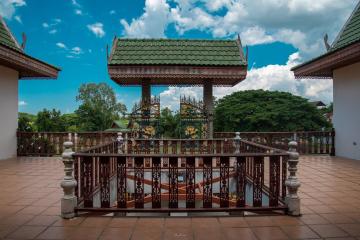 Spacious patio with traditional wooden railing and view of ornate rooftops against a cloudy sky