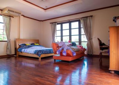 Spacious bedroom with large bed, wooden flooring, and air conditioning unit